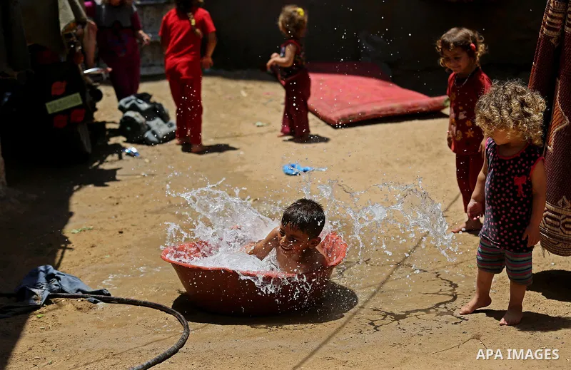 A Palestinian man washes his son outside his house during a heatwave in Beit Lahia in the northern of Gaza Strip, on July 4, 2017. Photo by Ashraf Amra
