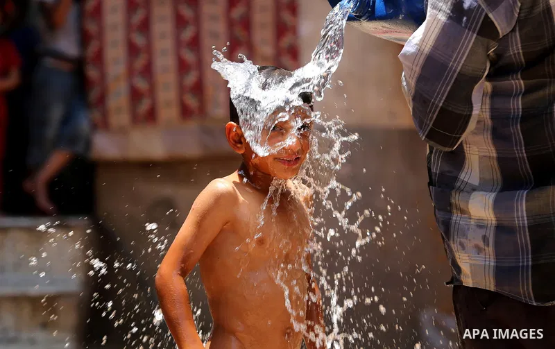 A Palestinian man washes his son outside his house during a heatwave in Beit Lahia in the northern of Gaza Strip, on July 4, 2017. Photo by Ashraf Amra