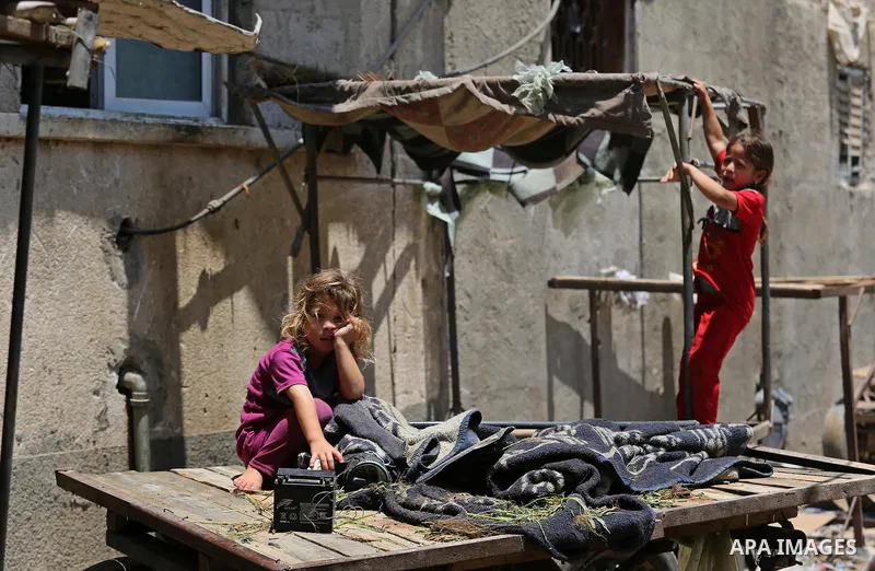 Palestinian girls stand outside their family house during a heatwave in Beit Lahia in the northern of Gaza Strip, on July 4, 2017. Photo by Ashraf Amra