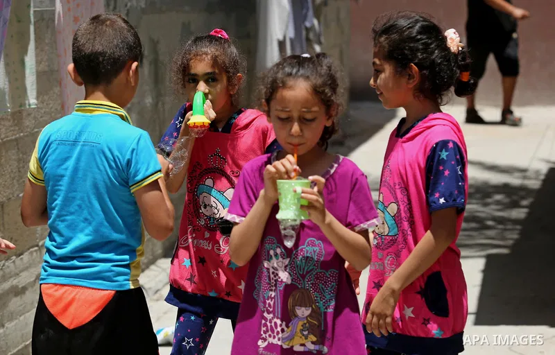 Palestinian children blow bubbles at street during a heatwave in Beit Lahia in the northern of Gaza Strip, on July 4, 2017. Photo by Ashraf Amra