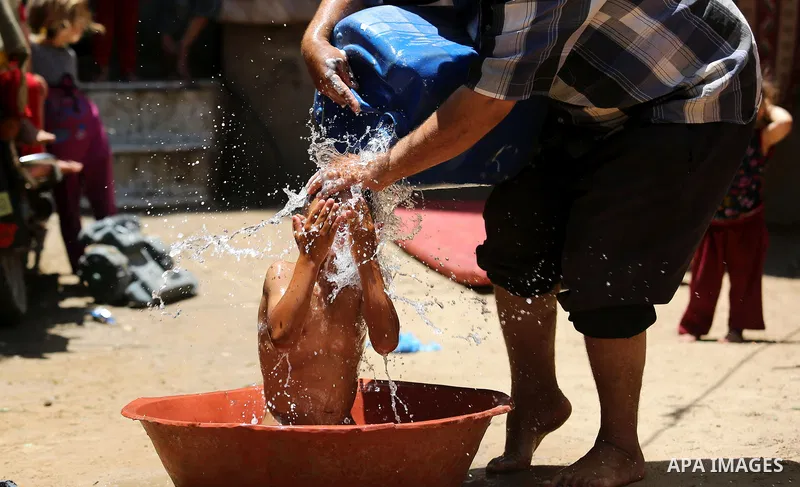 A Palestinian man washes his son outside his house during a heatwave in Beit Lahia in the northern of Gaza Strip, on July 4, 2017. Photo by Ashraf Amra