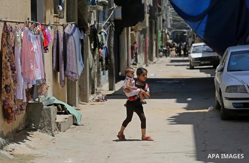 A Palestinian girl crosses the street during a heatwave in Beit Lahia in the northern of Gaza Strip, on July 4, 2017. Photo by Ashraf Amra