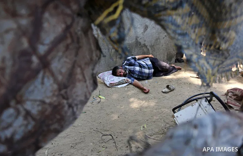 A Palestinian man lies down outside his house during a heatwave in Beit Lahia in the northern of Gaza Strip, on July 4, 2017. Photo by Ashraf Amra