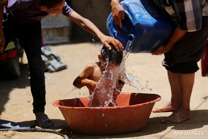 A Palestinian man washes his son outside his house during a heatwave in Beit Lahia in the northern of Gaza Strip, on July 4, 2017. Photo by Ashraf Amra