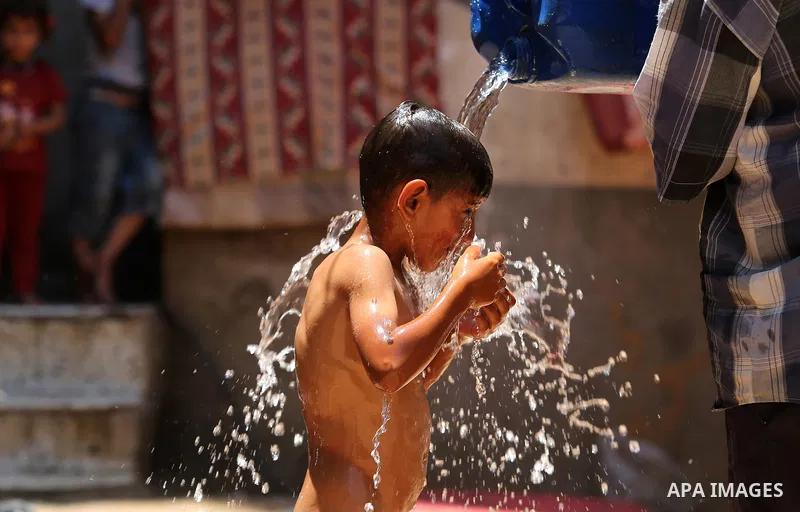 A Palestinian man washes his son outside his house during a heatwave in Beit Lahia in the northern of Gaza Strip, on July 4, 2017. Photo by Ashraf Amra