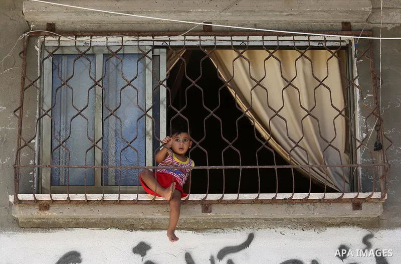 A Palestinian child looks through window at his family house during a heatwave in Beit Lahia in the northern of Gaza Strip, on July 4, 2017. Photo by Ashraf Amra