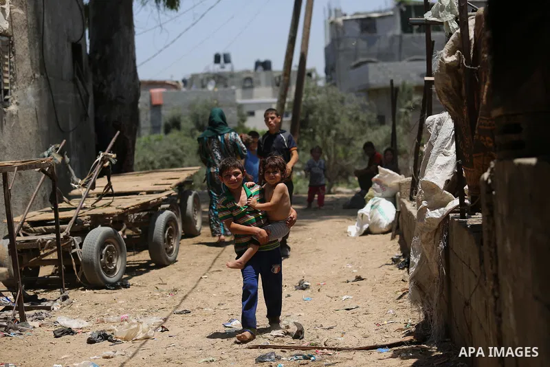 Palestinians walk at street during a heatwave in Beit Lahia in the northern of Gaza Strip, on July 4, 2017. Photo by Ashraf Amra