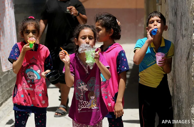 Palestinian children blow bubbles at street during a heatwave in Beit Lahia in the northern of Gaza Strip, on July 4, 2017. Photo by Ashraf Amra
