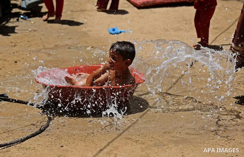 A Palestinian man washes his son outside his house during a heatwave in Beit Lahia in the northern of Gaza Strip, on July 4, 2017. Photo by Ashraf Amra