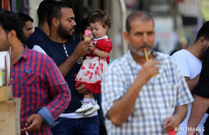 Palestinians eat ice-cream (sundae) in the street during a heatwave in Gaza city on July 4, 2017. Photo by Ashraf Amra