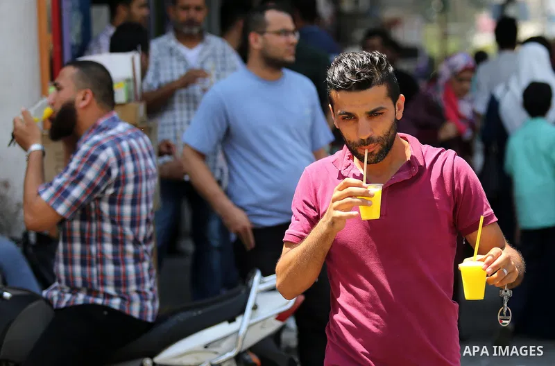 Palestinians eat ice-cream (sundae) in the street during a heatwave in Gaza city on July 4, 2017. Photo by Ashraf Amra