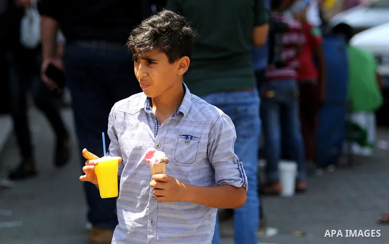A Palestinian boy buys ice-cream (sundae) during a heatwave in Gaza city on July 4, 2017. Photo by Ashraf Amra