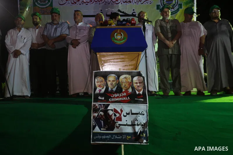Palestinians hold banners during a protest against Palestinian President Mahmoud Abbas and Israeli blockade of the Gaza Strip, in Gaza city, on July 4, 2017. Photo by Mohammed Asad