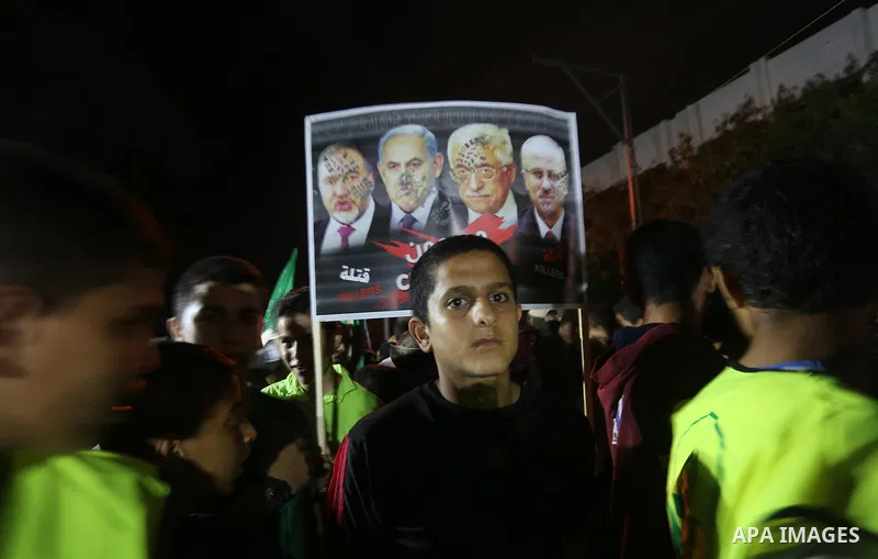 Palestinians hold banners during a protest against Palestinian President Mahmoud Abbas and Israeli blockade of the Gaza Strip, in Gaza city, on July 4, 2017. Photo by Mohammed Asad
