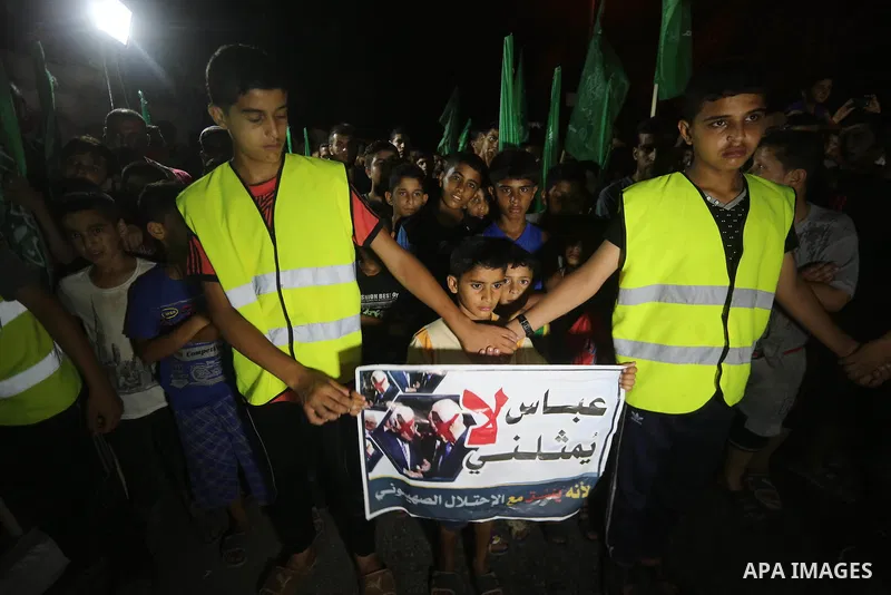Palestinians hold banners during a protest against Palestinian President Mahmoud Abbas and Israeli blockade of the Gaza Strip, in Gaza city, on July 4, 2017. Photo by Mohammed Asad