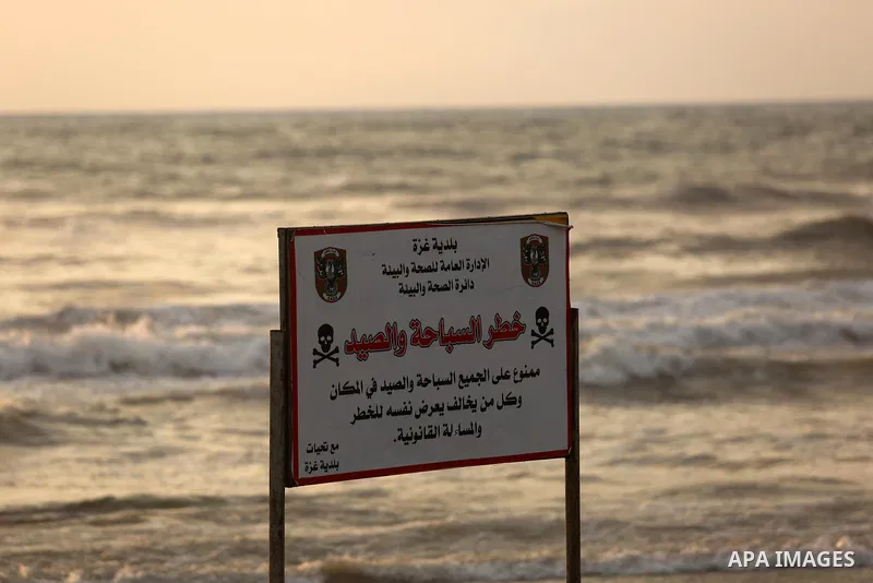 A warning sign reading 'dangerous swimming and fishing' is placed near an outlet flowing sewage into the sea in front of the coast of Gaza city, on July 5, 2017. An immediate consequence of the electricity cuts has been...