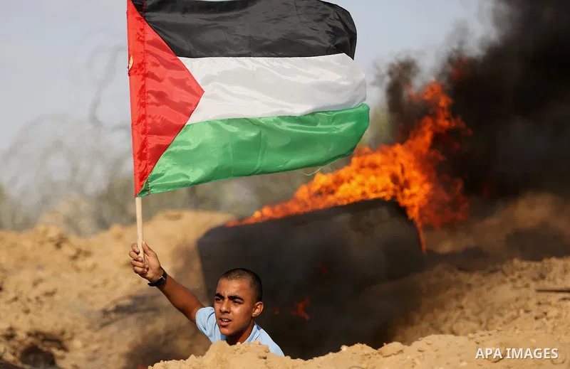 A Palestinian protester waves the national flag during clashes with Israeli security forces near the border between Israel and Central Gaza Strip July 7, 2017. Photo by Ashraf Amra