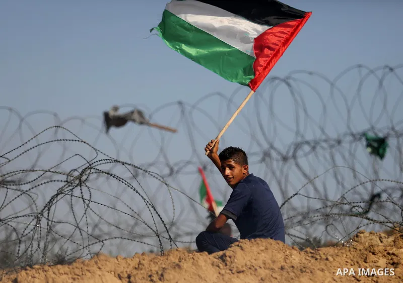 A Palestinian protester waves the national flag during clashes with Israeli security forces near the border between Israel and Central Gaza Strip July 7, 2017. Photo by Ashraf Amra