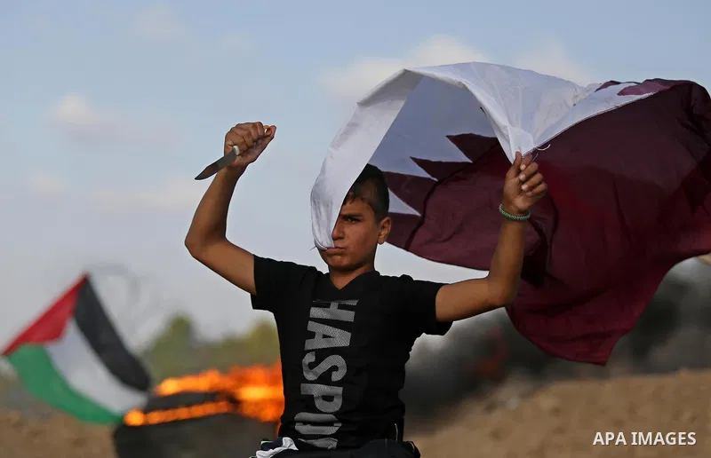 A Palestinian protester holds a knife and waves a Qatar flag during clashes with Israeli security forces near the border between Israel and Central Gaza Strip July 7, 2017. Photo by Ashraf Amra