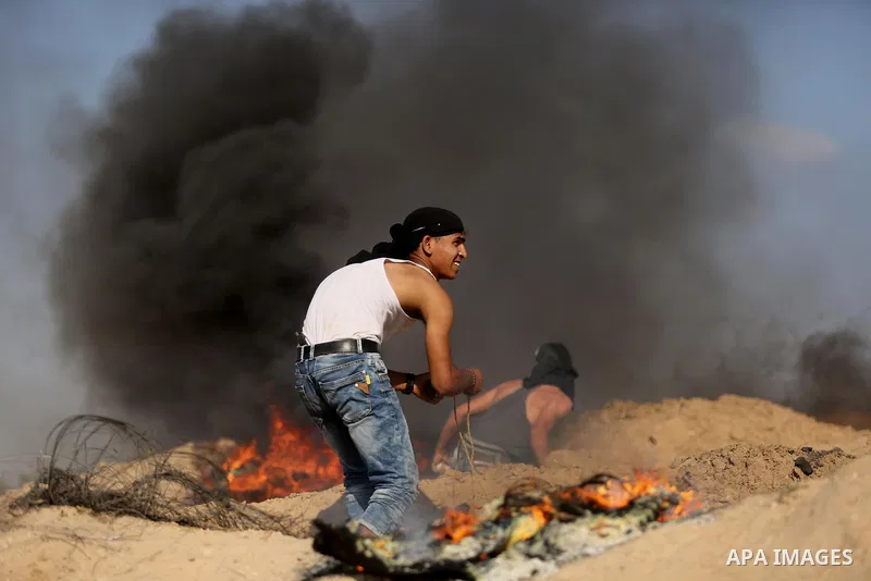 Palestinian protester take cover during clashes with Israeli security forces near the border between Israel and Central Gaza Strip July 7, 2017. Photo by Ashraf Amra