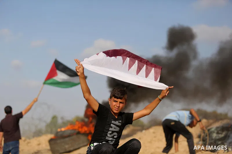A Palestinian protester waves a Qatar flag during clashes with Israeli security forces near the border between Israel and Central Gaza Strip July 7, 2017. Photo by Ashraf Amra