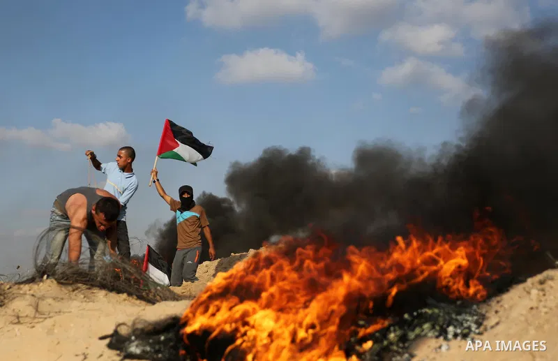 A Palestinian protester waves the national flag during clashes with Israeli security forces near the border between Israel and Central Gaza Strip July 7, 2017. Photo by Ashraf Amra