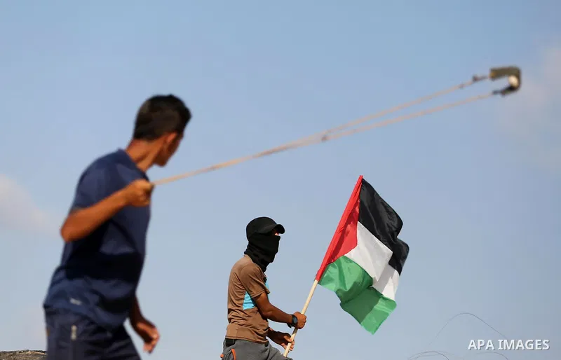 A Palestinian protester waves the national flag during clashes with Israeli security forces near the border between Israel and Central Gaza Strip July 7, 2017. Photo by Ashraf Amra