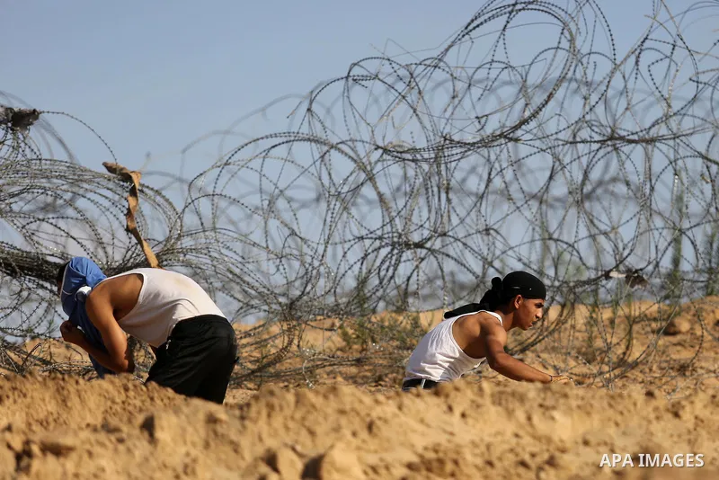 Palestinian protester take cover during clashes with Israeli security forces near the border between Israel and Central Gaza Strip July 7, 2017. Photo by Ashraf Amra