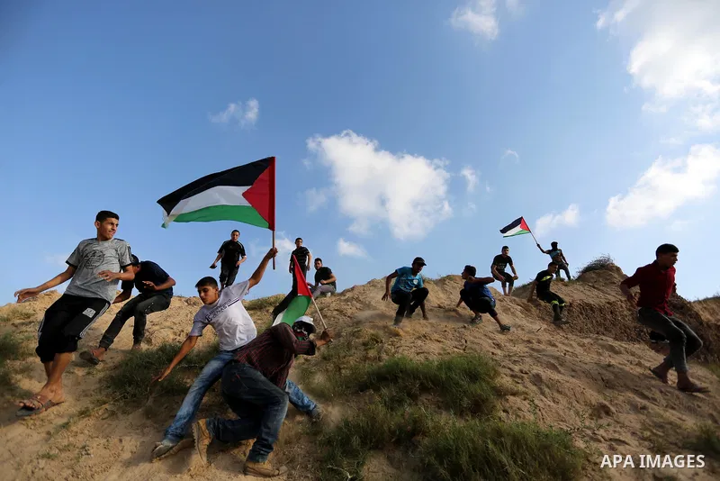 Palestinian protesters wave Palestine flags during clashes with Israeli security forces near the border between Israel and Central Gaza Strip July 7, 2017. Photo by Ashraf Amra