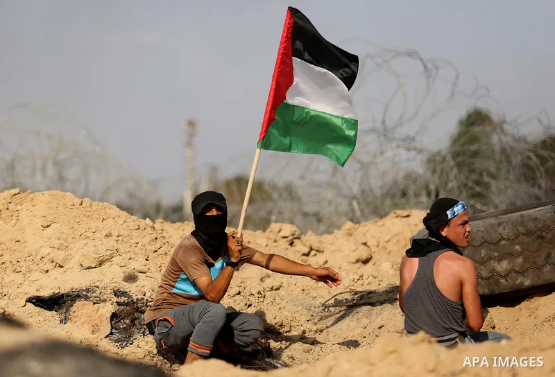 A Palestinian protester waves the national flag during clashes with Israeli security forces near the border between Israel and Central Gaza Strip July 7, 2017. Photo by Ashraf Amra