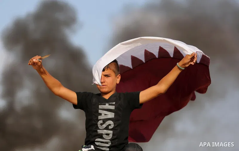 A Palestinian protester holds a knife and waves a Qatar flag during clashes with Israeli security forces near the border between Israel and Central Gaza Strip July 7, 2017. Photo by Ashraf Amra