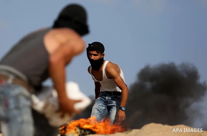 Palestinian protester take cover during clashes with Israeli security forces near the border between Israel and Central Gaza Strip July 7, 2017. Photo by Ashraf Amra