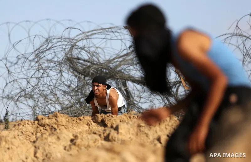 Palestinian protester take cover during clashes with Israeli security forces near the border between Israel and Central Gaza Strip July 7, 2017. Photo by Ashraf Amra