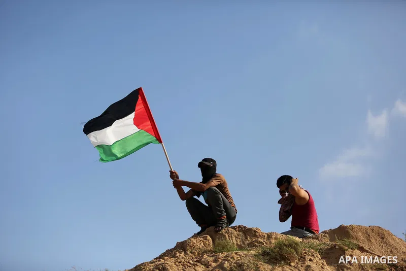 A Palestinian protester waves the national flag during clashes with Israeli security forces near the border between Israel and Central Gaza Strip July 7, 2017. Photo by Ashraf Amra