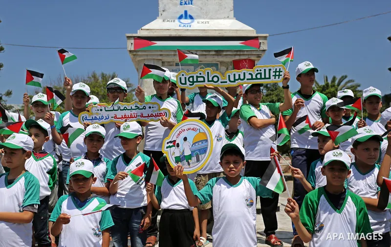 Palestinian children hold the national flags during the announcement the start of summer camps organized by the Hamas movement in Gaza city on July 8, 2017. Photo by Ashraf Amra