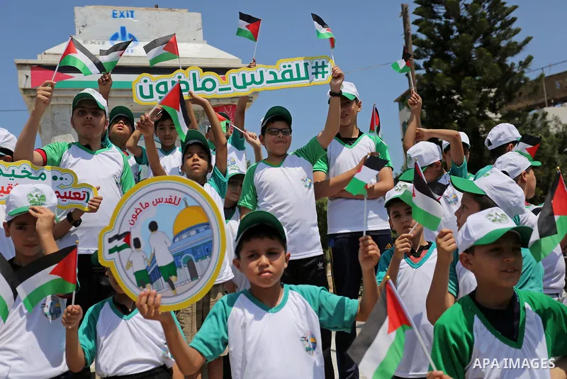Palestinian children hold the national flags during the announcement the start of summer camps organized by the Hamas movement in Gaza city on July 8, 2017. Photo by Ashraf Amra