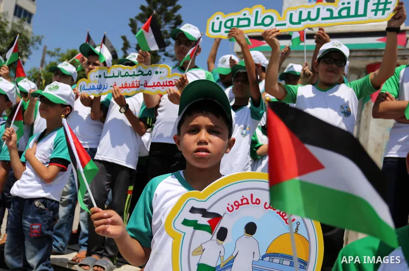 Palestinian children hold the national flags during the announcement the start of summer camps organized by the Hamas movement in Gaza city on July 8, 2017. Photo by Ashraf Amra