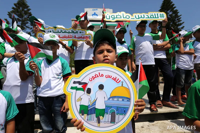 Palestinian children hold the national flags during the announcement the start of summer camps organized by the Hamas movement in Gaza city on July 8, 2017. Photo by Ashraf Amra