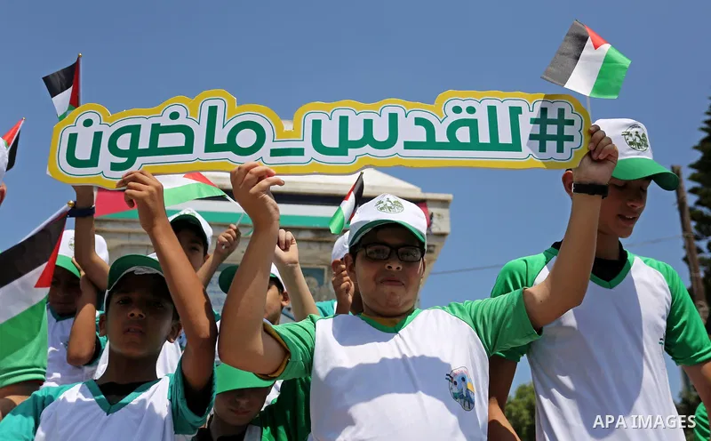 Palestinian children hold the national flags during the announcement the start of summer camps organized by the Hamas movement in Gaza city on July 8, 2017. Photo by Ashraf Amra
