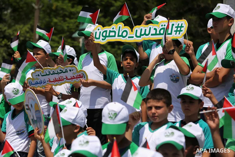 Palestinian children hold the national flags during the announcement the start of summer camps organized by the Hamas movement in Gaza city on July 8, 2017. Photo by Ashraf Amra
