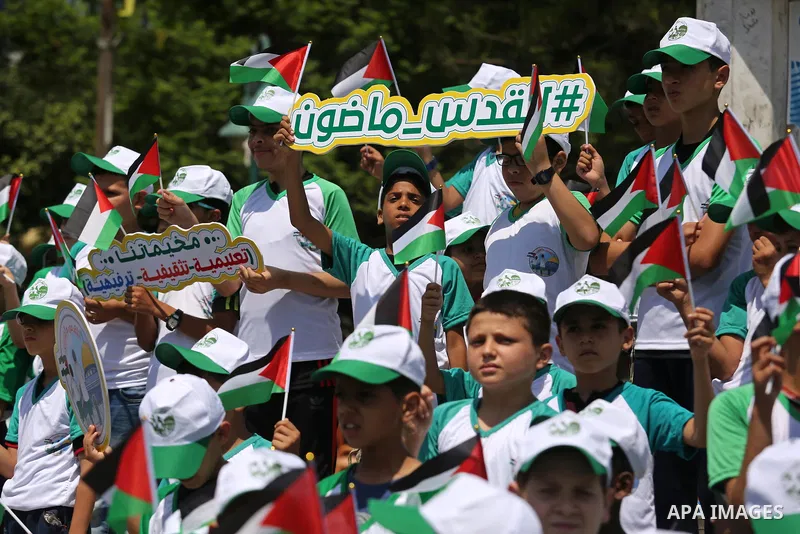 Palestinian children hold the national flags during the announcement the start of summer camps organized by the Hamas movement in Gaza city on July 8, 2017. Photo by Ashraf Amra