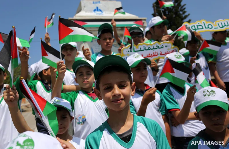 Palestinian children hold the national flags during the announcement the start of summer camps organized by the Hamas movement in Gaza city on July 8, 2017. Photo by Ashraf Amra