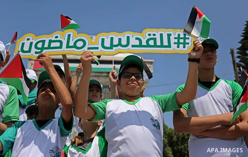Palestinian children hold the national flags during the announcement the start of summer camps organized by the Hamas movement in Gaza city on July 8, 2017. Photo by Ashraf Amra