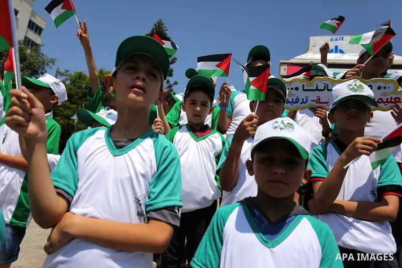 Palestinian children hold the national flags during the announcement the start of summer camps organized by the Hamas movement in Gaza city on July 8, 2017. Photo by Ashraf Amra
