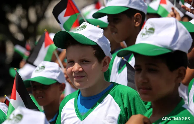 Palestinian children hold the national flags during the announcement the start of summer camps organized by the Hamas movement in Gaza city on July 8, 2017. Photo by Ashraf Amra