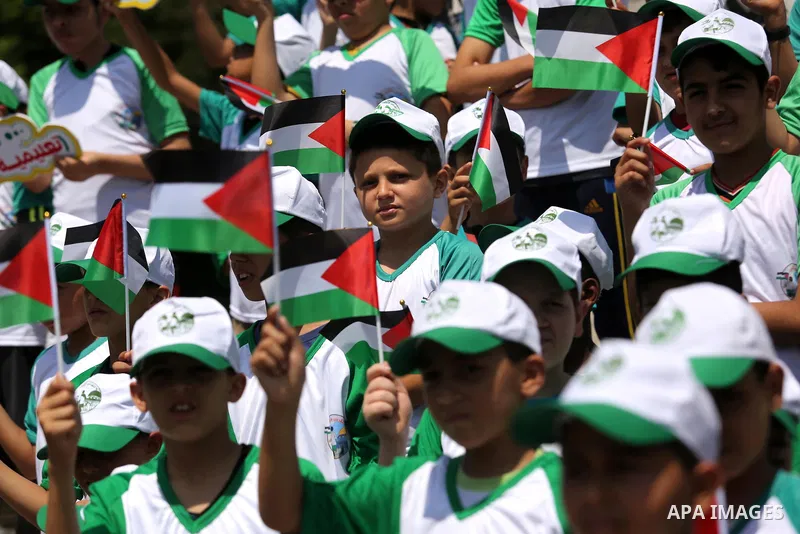 Palestinian children hold the national flags during the announcement the start of summer camps organized by the Hamas movement in Gaza city on July 8, 2017. Photo by Ashraf Amra