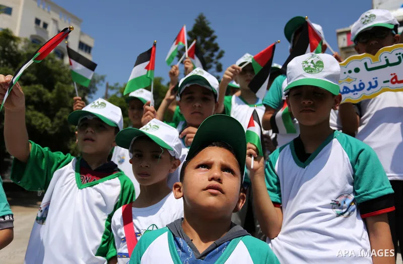 Palestinian children hold the national flags during the announcement the start of summer camps organized by the Hamas movement in Gaza city on July 8, 2017. Photo by Ashraf Amra