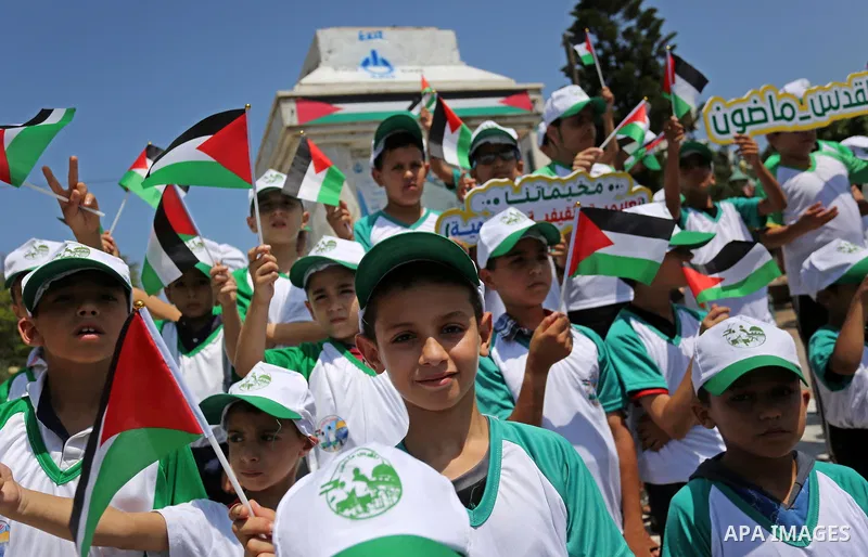 Palestinian children hold the national flags during the announcement the start of summer camps organized by the Hamas movement in Gaza city on July 8, 2017. Photo by Ashraf Amra