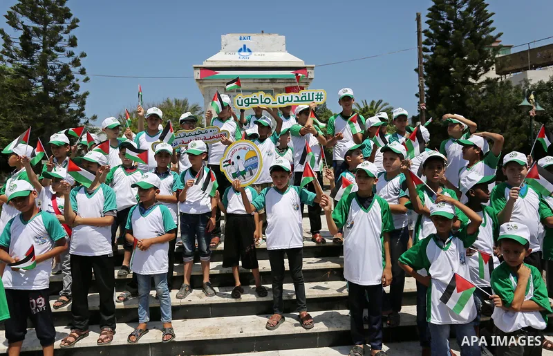 Palestinian children hold the national flags during the announcement the start of summer camps organized by the Hamas movement in Gaza city on July 8, 2017. Photo by Ashraf Amra