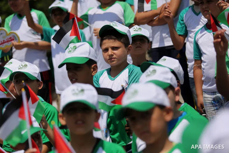 Palestinian children hold the national flags during the announcement the start of summer camps organized by the Hamas movement in Gaza city on July 8, 2017. Photo by Ashraf Amra
